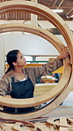 Carpenter, woman and quality in workshop, wood craft or production inspection with circle frame. Woodwork, person and check for furniture manufacturing, design or structural integrity evaluation