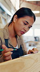 Carpenter, woman and measurement in workshop with wood, pencil and ruler for precision or process. Serious, woodworking and manufacturing in factory for handmade, custom and production of design
