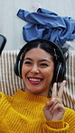 Woman, headphones and selfie in home with peace sign, relax and social media post on weekend break. Above, gen z person and happy in bedroom with audio tech, photography or blow kiss for online blog.