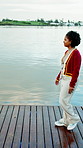Woman, walking and laughing in nature, lake and happy on peaceful vacation and adventure on weekend. Outdoor, water and person with smile on break, thinking and remember good memory on holiday