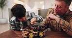 Dad, boy and building with toy car in home for assembling parts, bonding or fun activity together. Father, child or helping son on electrical motor vehicle for junior engineering or learning in house