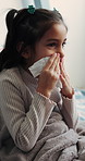 Tissue, sneeze and child blowing nose in bedroom with allergies, flu or viral infection in home. Sick, illness and girl kid with toilet paper for sinusitis, cold or medical virus in bed at house.