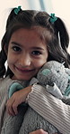 Face, kid and hug in home with teddy bear, comfort or play on weekend break for child development. Happy little girl, embrace stuffed animal or cuddle plush toy in house with love, care and innocence
