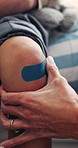 Mother, hands and kid with bandage for knee injury, first aid assistance and wound protection in home. Caring woman, child and help in house with plaster application, safety or hurt leg from accident