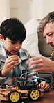 Boy, dad and toy car with electrical cables in home for engineering or remote control vehicle. Child, kid or learning with father to build robotic transportation for junior mechanic or development