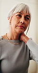 Senior woman, hurt and neck pain in house, discomfort and unhappy with muscle sprain or inflammation. Retirement, reflection and old person with injury, joint tension and arthritis symptoms in home