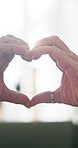 Couple, love and heart hands with shape in home for romance, support or commitment together. Relationship, man and woman with like emoji, lens flare or romantic gesture for date or care in house