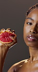 Beauty, face and grapefruit with black woman in studio for diet, health benefits or nutrition. Food, juice and squeeze with serious person on dark background for detox, skincare or vitamin c