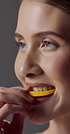 Skincare, orange or woman with bite, vitamin c benefit or nutrition in organic wellness. Diet, collagen or happy person on studio background with fruit, gut health or antioxidant in natural cosmetics
