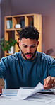 Stress, man and reading at house with documents, finance report and pressure of overdue bills. Frustrated, person and crisis in home with paperwork, financial burden and debt increase for bankruptcy