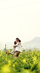 Couple, hug and spin in field with flowers, love connection and excited for relationship commitment. Mockup space, happy married people and embrace outdoor in countryside with plants, lift and trust.