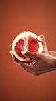 Person, hands and playing with grapefruit in studio for sensual arousal on a orange background. User, fruit or playful seduction with food for sexual stimulation, foreplay or menstrual ovulation