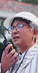 Architect, woman and speaking at construction site with radio, instructions and project management. Mature person, talk and tech outdoor with communication, architecture and guidance for building.