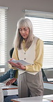 Woman, teacher and walk in classroom with document, assignment and school quiz for education. Person, teaching and students at campus with paperwork, exam revision and assessment results for learning