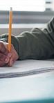 Person, student and hands writing with book in classroom for exam, test or assessment. Notebook, pencil or academic learner with paper or notes for multiple choice, question or answer in school