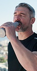 Fitness, outdoor and mature man with water bottle on break, rest and exhausted after intense workout. Male person, tired athlete and drinking to hydrate for wellness, health and exercise in summer