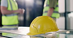 Hardhat, desk and hands of construction workers on site with discussion for PPE or safety compliance. Helmet, people and civil engineer with contractor for building, renovation or repairs feedback.