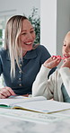 Happy, mom and laughing with child for homework, fun learning or joke together in home. Mother, kid or tutor teaching daughter with smile, comedy or book for education, development or humor in house