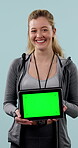 Face, green screen and tablet with personal trainer woman in studio for development or training. App, mockup space and stop watch with happy coach on blue background for health or workout results