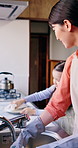 Mother, girl and washing dishes in home for routine, soap and disinfection in kitchen cleaning. Asian mom, daughter and teaching child responsibility or support, bonding and housework for hygiene