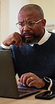 Businessman, glasses and plan with laptop in office, research or reading financial report on website. Serious, mature accountant and black person with technology for budget review and reflection
