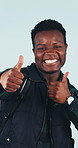 Hiking, face and happy man with thumbs up in studio, opinion or recommendation for holiday adventure. Blue background, dancing and black person with smile, backpacking and approval for travel tips