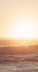 Sunset, ocean and waves at beach for travel destination, natural environment and high tide on island. Flare, outdoor and evening by sea with water movement, vacation location and peaceful landscape.