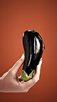 Eggplant, hand and lubrication with person on studio background for pleasure or sensuality. Demonstration, liquid gel on fruit and passion with woman on backdrop for preparation or sexuality