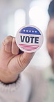 Hands, person and political badge for vote, election day and participation for equality awareness. Smile, woman or button in workplace for voting rights, social responsibility and democratic campaign