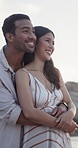 Couple, smile and hug by beach with summer holiday, conversation and travel for romantic getaway. Happy, people dating and embrace outdoor by ocean with love, relationship or discussion for vacation.