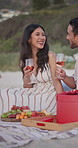 Couple, relax and laugh at beach with alcohol, picnic and romantic anniversary for summer holiday. Happy, people and discussion at sea with wine, getaway date and partner celebration on vacation trip