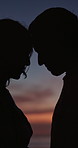 Sunset, beach and couple with forehead touch for bonding, love and connection on anniversary holiday. Silhouette, sky and man with woman for affection, commitment or care by ocean on vacation.