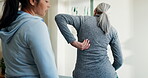 Back pain, talking and women in physical therapy session for healing, consultation and healthcare. Person, senior patient and spine injury with rehabilitation, chiropractic and joint wellness