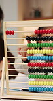 Abacus, counting and hand of girl in home with mother for child development, homework or learning. Education, maths and woman teaching daughter at counter in apartment for knowledge or numeracy