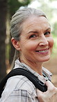 Hiking, face and mature woman in forest for trekking, backpacking and explore for adventure. Happy, portrait and person with smile for fitness, exercise and travel for fresh air, wellness and health