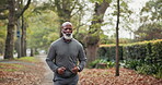 Exercise, running and man with headphones at park for health workout, morning cardio or playlist. Active, mature black person and jogging in nature for fitness, physical activity and music streaming