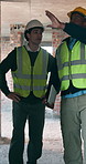 Talking, planning and men in building for construction, remodeling and renovation project. Architecture, contractor and people walking on site for property development, progress and engineering idea