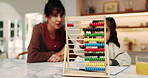 Mother, helping and child in home with abacus, math lesson and counting for education. Mature woman, tutor or kid at house with academic toys, learning support and calculating beads for study session