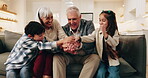 Happy, grandparents and hands together with children on sofa for teamwork, mission or bonding in home. Grandma, grandpa and kids piling with smile, stack or love for unity, trust or support in house