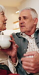 Tea, talk and senior couple with laugh in home for funny story, healthy marriage or connection. Love, happy people or conversation with drink in house for bonding together, retirement support or joke