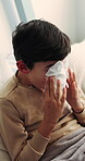 Tissue, sick and child blowing nose in bedroom with allergies, flu or viral infection in home. Sneezing, illness and boy kid with toilet paper for sinusitis, cold or medical virus in bed at house.