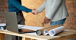 Blueprint, building and laptop with businesspeople shaking hands on construction site for agreement. Computer, deal and handshake architect team on worksite for greeting, partnership or thank you