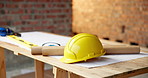 Architecture, helmet and blueprint at empty site for building, maintenance or property development. Hard hat, floor plan and equipment with PPE on desk by construction design for repair or renovation