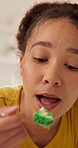 Eating, cake and woman on break in home, craving and relax with tasty snack and junk food in kitchen. Morning, treat and person with sweet tooth, thinking or satisfied with delicious dessert in house