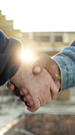 Handshake, construction site and people in partnership with flare, agreement and welcome for building. Team, architecture and shaking hands for engineering, infrastructure and introduction outdoor