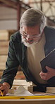 Carpenter, man and writing on document in workshop for development guide, construction or blueprint. Asian person, mature and layout paperwork for woodwork, building design or review requirements