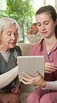 Nursing home, old woman and nurse with tablet, talking and explaining medical schedule on app or web. Healthcare, caregiver and senior person with tech, happy and help with telehealth appointment