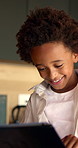 Boy, tablet and smile with typing in home for educational games, puzzle app and relax in kitchen. African child, happy and digital tech with development, streaming or subscription for video in house
