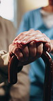 Nurse, senior and holding hands with cane for assisted living, healthcare or support in house. People, caregiver or health worker with patient for elderly care, understanding or trust in old age home