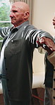 Physiotherapy, stretching and senior man with help for health, shoulder rehabilitation and care. Retirement, elderly person and physiotherapist in office with joint mobility and progress assessment